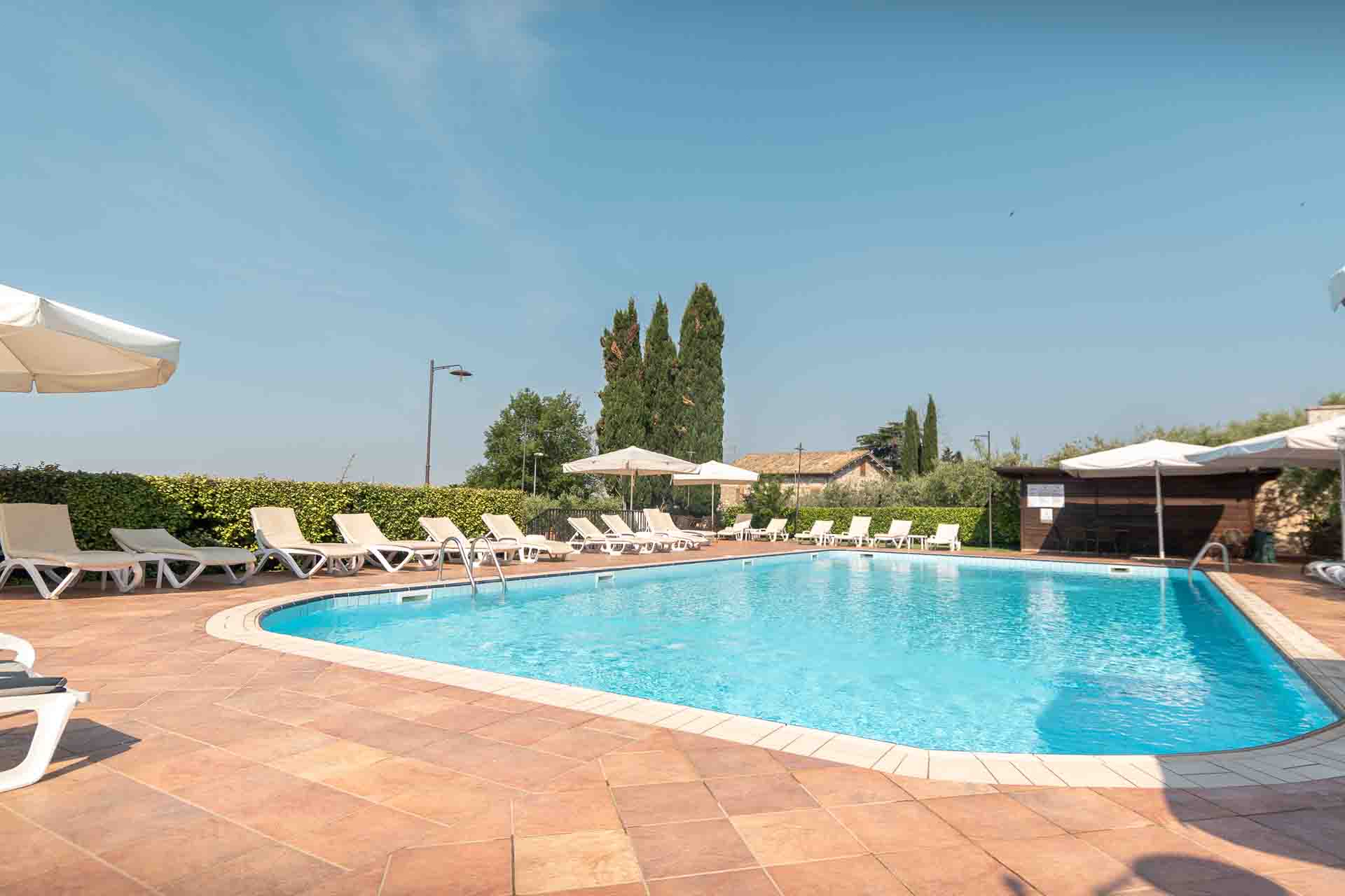 Piscina esterna con zona relax in hotel tre stelle con centro benessere e ristorante ad Assisi